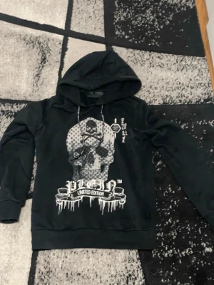 Svart hoodie med döskalletryck - Säljer en svart hoodie med stor döskalle och texten 'Limited Edition' framtill. Hoodien har huva med dragsko och ribbade muddar vid ärmar och nederkant. Trycket är i vitt och ger en edgy streetwear vibe.