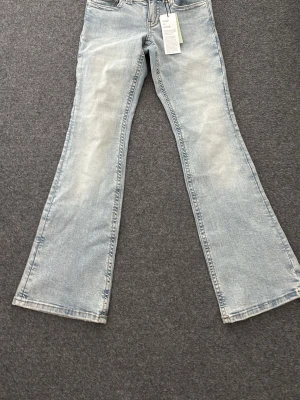 Ljusblå utsvängda jeans - Säljer ett par ljusblå bootcut jeans med klassisk femficksdesign och snygga slitningar framtill. Perfekta för dig som gillar bootcut jeans.