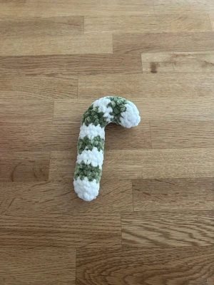 Virkad polkagris  - Handgjord virkad polkagris i grönt och vitt, tillverkad av mjukt garn. Perfekt som dekoration till jul eller som en söt detalj i hemmet. Formen är klassisk böjd polkagris och materialet är fluffigt garn.