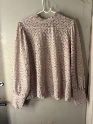  spetsblus  - Supersöt beige blus i spets med diskret mönster och högt halsringning. Blusen har långa puffärmar med breda muddar och en lös passform. Perfekt för dig som gillar romantisk och vintage-inspirerad stil. Den perfekta blusen till höst!🤎