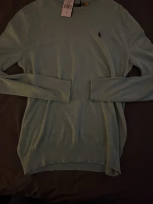 Ljusgrön stickad tröja Polo Ralph Lauren - Snygg ljusgrön stickad tröja från Polo Ralph Lauren i slim fit-modell. Tröjan har rund halsringning, långa ärmar och den klassiska lilla logotypen broderad på bröstet. Perfekt för dig som gillar stilrena och tidlösa plagg. Köpt på volt, helt oavnävd. Nypris 2295 kr