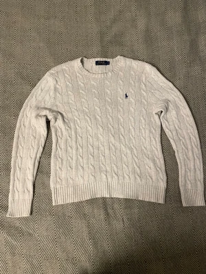 Ralph Lauren kabelstickad tröja - Ljusgrå kabelstickad tröja från Polo Ralph Lauren. Storlek small, gott skick. Skriv gärna vid minsta fundering! Postar inom 24 timmar.