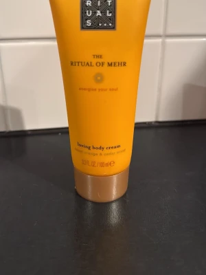Rituals The Ritual of Mehr loving body cream - Fräsch body cream från Rituals i serien The Ritual of Mehr. Kommer i en orange tub på 100 ml med guldigt lock. Doftar söt apelsin och cederträ, perfekt för dig som vill ha en energigivande och återfuktande hudkräm. Oanvänd 