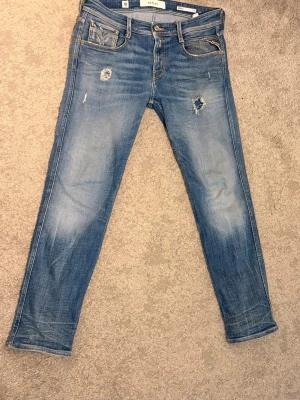 Replay Anbass Jeans - Snygga Replay Anbass jeans i storlek W30. Klassisk blå denim med snygg slitning och detaljer som ger jeansen en schysst vintage-look. Modellen är Anbass, som sitter slim/modern på kroppen.  * Storlek: W30 * Märke: Replay * Modell: Anbass * Färg: Blå * Fint skick, se bilder för skick och detaljer * Äkta Replay  📦 Skickas snabbt och packas väl! 💬 Hör gärna av dig om du har frågor eller vill ha fler mått/bilder.