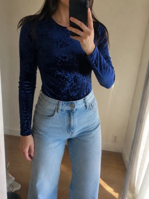 Forever 21 blå sammetsbody 💙 stl S - Snygg mörkblå topp i mjuk sammet med lång ärm och rund halsringning. Materialet har en glansig finish som ger en lyxig känsla och toppen har en figurnära passform. Perfekt att styla med jeans eller kjol för en trendig look.