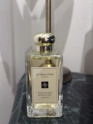 Jo Malone English Oak & Hazelnut - Exklusiv parfym från Jo Malone, English Oak & Hazelnut. Flaskan är rektangulär i genomskinligt glas med silverfärgad rund kork. Medföljer originalförpackning och elegant presentpåse. Doften är fräsch och träig med inslag av hasselnöt Ny pris 1700 kr men jag säljer 1399 kan komma när vid snabb affär. Doften är jätte djup och elegant men passade tyvärr inte mig har bara testsprutat