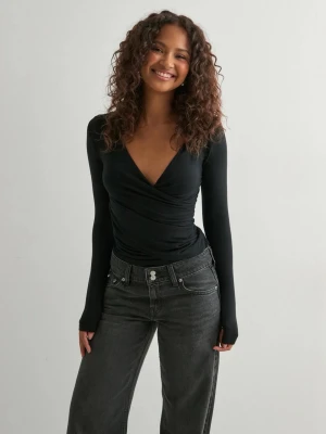 Svart omlottopp med v-ringning från Nelly - Snygg svart omlottopp från Nelly med tight passform och är tillverkad i ett mjukt, stretchigt material som sitter skönt på kroppen. Perfekt att styla med jeans eller kjol för en trendig look. Har aldrig använts!!❤️❤️