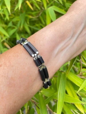Svart och silverfärgat länkarmband i rostfritt stål  - Snyggt armband med svarta gummidetaljer och silverfärgade länkar i metall. Armbandet har en modern, stilren italiensk design med rektangulära länkar som ger en cool och edgy känsla. Perfekt accessoar för att lyfta din outfit. Total längd 21 cm och bredd ca 12 mm 