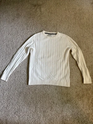 Stock & Hank Kabelstickad Tröja  - Vit kabelstickad tröja från Stock & Hank i mycket fint skick. Klassisk modell som passar perfekt tillsammans med jeans eller chinos.  ✔️ Storlek S ✔️ Kabelstickad ✔️ Mycket fint skick  📦 Skickas snabbt.