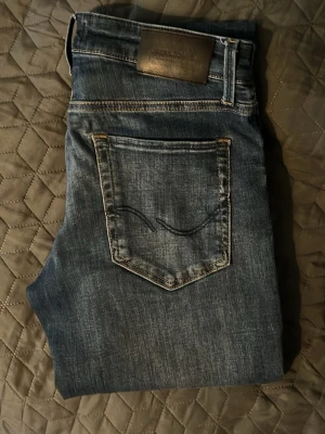 Mörkblå slim fit jeans herr - Säljer ett par mörkblå slim fit jeans med klassisk femficksdesign och smal passform. Jeansen har normal midja och är tillverkade i ett stretchigt denimtyg för extra komfort. Perfekta för en avslappnad och trendig stil.