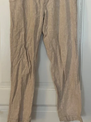 Beige linnebyxor raka ben - Säljer ett par stilrena beige linnebyxor med raka ben och klassisk passform. Perfekta för varma dagar och enkla att matcha med olika toppar. Luftigt material som ger en avslappnad vibe. Nypris är 599kr.