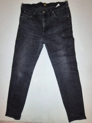 Lee Austin jeans gråsvarta W36 L34 regular  - Snygg modell från Lee i modellen Austin, regular tapered fit bekvämare upptill och avsmalnande nedåt.  Stretchigt tyg med klassisk 5-ficksmodell, knapp/dragkedja, bälteshällor och Lee-detaljer.  Märke: Lee Modell: Austin Storlek: W36 L34 Färg: Gråsvart/svart 