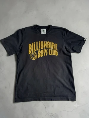 Billionaire Boys Club t-shirt - Säljer en riktigt schysst svart t-shirt från Billionaire Boys Club med det ikoniska trycket i guld på bröstet samt den lilla astronauthalsloggan bak. Armhåla till armhåla ≈54cm. Längd ≈70cm Självklart äkta! Hör av er vid fler frågor!