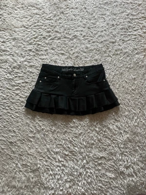 svart volangkjol  - En lite glansig svart jeanskjol omsydd från ett par jeans.   Midjemått tvärsöver- 38cm (stretchig) Längd -28cm