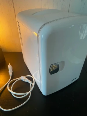 Vitt minikylskåp (SMEG-kopia) med sladd - Säljer ett kompakt och stilrent minikylskåp i vit plast med rundade hörn och enkel design. Perfekt för att kyla drycker eller snacks på rummet. Kylskåpet har ett handtag på dörren och strömkabel medföljer. OBS! Har även en värmefunktion så man kan använda den till varmhållning. 