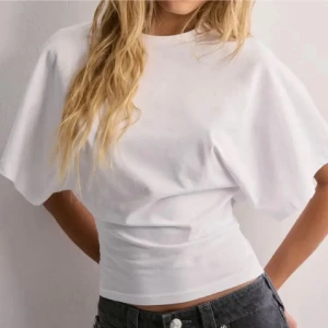 t-shirt med vida ärmar - Snygg vit t-shirt med vida, korta ärmar och rund hals. T-shirten har en tight passform i midjan