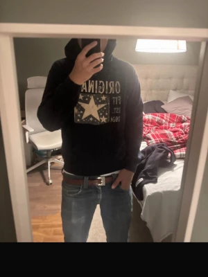 Est original hoodie - Säljer en marinblå hoodie med huva och magficka. På bröstet finns ett stort tryck med texten 'ORIGINAL FIT EST. 2024' och en stor stjärna i mitten. Hoodien har en avslappnad passform och är perfekt för en chill look. Materialet ser ut att vara mjukt bomullstyg.