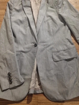 Ljusgrå kavaj - Stilren ljusgrå kavaj från Tiger of Sweden med klassisk passform. Lång modell.     #baggyjeans #lowwaist jeans #cargobyxor #vida jeans #flarejeans #lågmidja #rakajeans #kostymbyxor #mjukisbyxor #oversizedhoodie #ziphoodie #stickadtröja #corsettopp #offshoulder #babytee #linne med spets #oversized tshirt #stickadväst #maxikjol #y2k #vintage #streetwear #oldmoney #cleangirl #basic #festkläder #vardagskläder #unisex #oversized #fitted #cozy #retro #zara #hm #bikbok #ginatricot #nelly #nakd