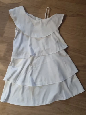 Vit volangklänning från Gina Tricot - Superfin vit klänning från Gina Tricot. Passar mig som bär S.   #baggyjeans #lowwaist jeans #cargobyxor #vida jeans #flarejeans #lågmidja #rakajeans #kostymbyxor #mjukisbyxor #oversizedhoodie #ziphoodie #stickadtröja #corsettopp #offshoulder #babytee #linne med spets #oversized tshirt #stickadväst #maxikjol #y2k #vintage #streetwear #oldmoney #cleangirl #basic #festkläder #vardagskläder #unisex #oversized #fitted #cozy #retro #zara #hm #bikbok #ginatricot #nelly #nakd