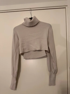 Beige  polotröja stickad - Trendig beige cropped stickad polotröja med långa ärmar och breda ribbade muddar. Polokrage och ribbstickad struktur ger en snygg och modern look. Perfekt för lager på lager och passar till både jeans och kjol. Den ska vara en storlek L men skulle säga att den är en S/M och inte en L 