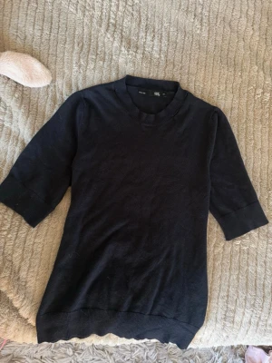 mörkblå stickad topp - mörkblå stickad topp med korta ärmar, superskönt material och bra basplagg att matcha med mycket smycken och snygga jeans