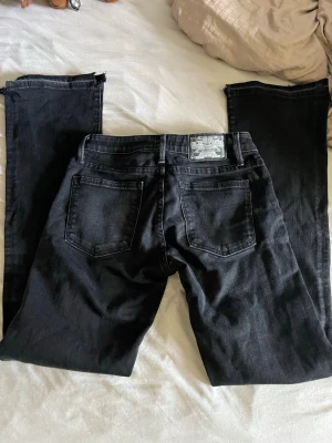 Svarta Utsvängda jeans - Säljer ett par svarta lågmidjade utsvängda jeans eftersom dom är för korta för mig (jag är 172) Det är sönder vid hälarna (se sista bilden). Svarar gärna på frågor och pris kan absolut diskuteras vid snabbt köp. Är 26/31 passar XS och S❣️