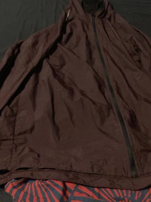 Mörkbrun vindjacka med dragkedja - Säljer en mörkbrun vindjacka med hel dragkedja framtill och hög krage. Jackan är tillverkad i 100% nylon vilket gör den lätt och smidig. Perfekt för blåsiga dagar när du vill ha något enkelt och stilrent. Inga sprickor bra skick men tyvärr ingen användning alls Kan även ha den på idrotten ute Hämtas I Västerås Flocksta 3 ändas swhis 