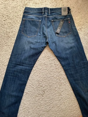 Mörkblå raka jeans från Replay - Snygga mörkblå jeans från Replay med raka ben och klassisk femficksmodell. Jeansen har kontrastsömmar och en diskret tvätt för en avslappnad look. Tillverkade i slitstarkt denimtyg med bälteshällor och Replay-tag på bakfickan. NOTERA HÅLEN PÅ BAKSIDAN❗️❗️
