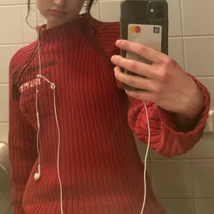 Röd stickad tröja - jätte cool långärmad röd tröja, med lite coola designer på bröstet med en liten dragkedja från halsen.