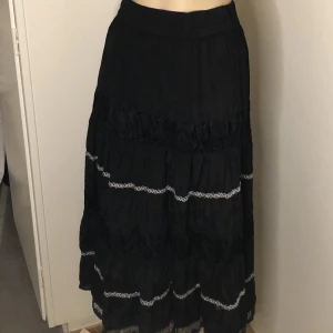 Kjol - Svart lång kjol med spets och silverdetaljer. Resårband vid midjan. Bra skick!