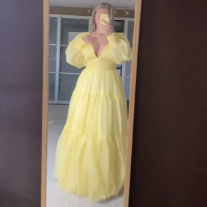 Balklänning  - Gul klänning med flera lager tyll. Håller upp bysten bra. Tunna fladdriga ärmar men åtsittande vid handleden. Låg rygg (finns ett gömt spänne om man vill ha den lite tajtare i ryggen) Klänningen är måttbeställd över bysten samt midjan (skriv för mått)