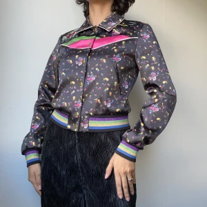 Blommig Jacka - • EXCLUSIVE DARK PURPLE SATIN, FITTED JACKET WITH FLOWER PRINT AND EMBROIDERY  • SIZE - XS / EU 34 • BRAND - & Other Stories  • MATERIAL - 93% Polyester, 7% Elastane. Lining: 52% Polyester, 48% Viscose   lila rosa svart grön blå guld silver glitter mönste