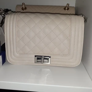 beige väska  - Beige väska med silvriga detaljer❤Ser nästan som ny ut, bara lite skavanker/repigt på vridlåset-knappt märkbart(se bild 3). Köpt här på plick men har ej kommit till användning så därför säljer jag vidare den. BILD 2   FRÅN   FÖRRA   ÄGAREN!  Frakt: 66 kr 