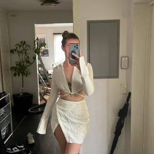 Vitt set med topp och kjol  - Super fint vitt set från prettylittlething med kjol med slits och en topp man kan knyta på olika sätt. Perfekt till sommaren eller kanske till studenten. Detta set är oanvänd med lappar kvar. 