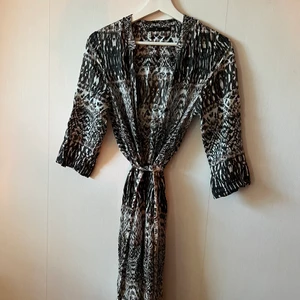 Klänning  - Mönstrad klänning med knyt i midjan.