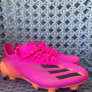 Adidas X GHOSTED.1SG SUPERSPECTRAL - Fotbollsskor som endast är använda en kort stund, enda slitaget är dubbarna som tappade lite färg efter att ha gått på asfallt. Inköpta för 2300kr. Kommer ej i originalförpackning. rosa/orange/svart. 