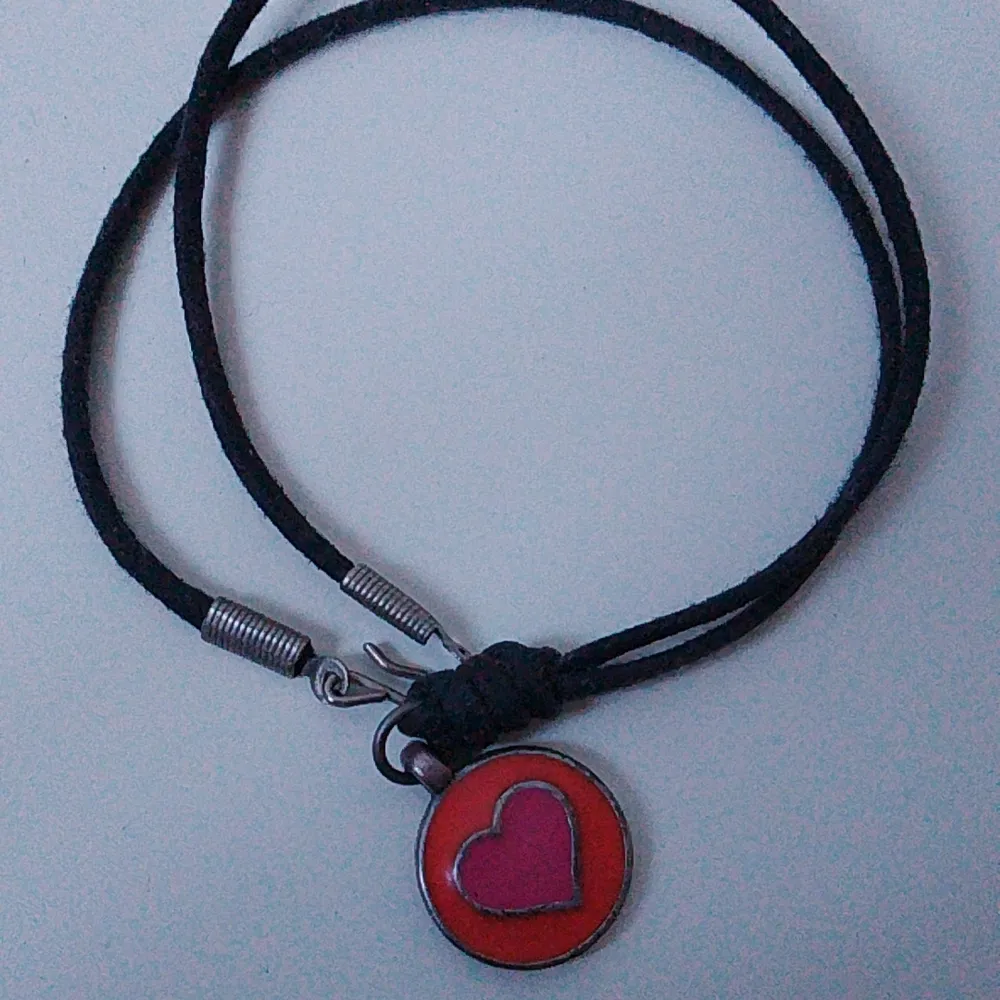 Kort halsband med läderrem och en berlock med ett hjärta . Accessoarer.