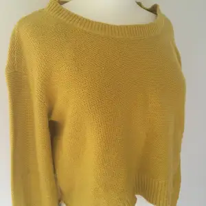 Det är en gul stickad tröja med bred urringning. På mig slutar tröjan ungefär under naveln. 