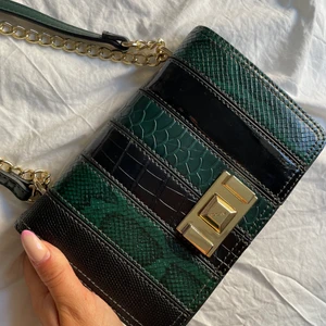 Väska  - Väska köpt utomlands, använd en gång så är i nyskick! Mörkt grön med svarta detaljer, kan ha kort och lång med bandet. Kan mötas i Stockholms området eller skicka! 