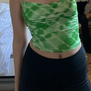 Grön topp med lite öppen rygg - En grön tie dye aktie topp med ryggen öppen där man korsar banden för att få en snygg design där bak. Banden går att dra åt hur mycket man vill och toppen är verkligen jättefin