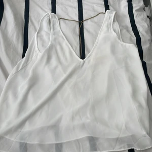 Vitt linne med guld detalj  - Säljer nu mitt fina vita linne med en guld kedja som en jätte fin detalj från Bikbok. Tröjan har en liten fläck som ska gå bort i tvätten, Väldigt bra skick annars. Storlek S