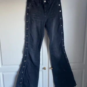 Utsvängda jeans med knappar - Utsvängda svarta jeans med knappar från NA-KD, strl 36