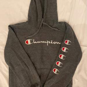 Säljer en mörkgrå Champion hoodie med coolt tryck på både framsidan och ärmen. 