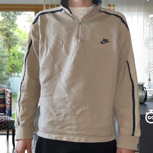 Nike Halfzip Vintage - En krämig beige Nike halfzip med svarta inslag. Bänger tröja ska inte ljuga och väldigt väldigt bra skick. Storlek XL men passar L och funkar på mig som är M. Men är såklart lite oversize på mig. (Är 188 förresten)