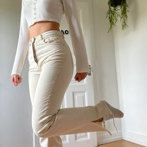 Beiga jeans med slits - Ett par beiga jeans från NA-KD. Använda endast två gånger därav i väldigt bra skick. Jag är 174 cm lång, se bild för längd💫