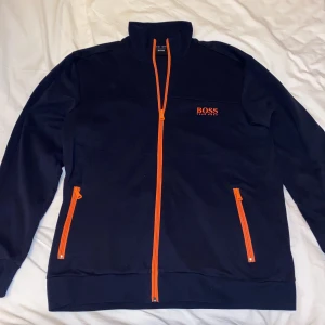 Hugo boss sweatshirt strl M  - Tröjan är i nyskick 10/10. Använd 2 gånger. Köptes för 1 år sen på hugo boss butiken i Stockholm för 1600 kr och jag säljer den nu för 699kr. Marinblå/orange 