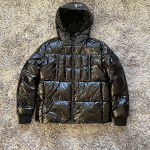 CALVIN KLEIN DUNJACKA - Calvin Klein dunjacka. Glansig svart. Storlek L men sitter mer som M. Den är bara använd någon gång och säljer pga för liten storlek. Nypris 2 599:-