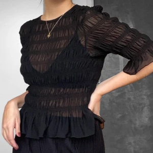 Topp - Svart gullig topp från Gina Tricot i tunt material. Strl M och i stretchigt material. Felfri och sparsamt använd 