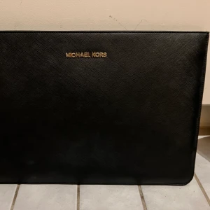 Michael kors datorfodral  - Datorfodral till MacBook Air 13 tum. Svart med guldetaljer. Fint skick, använt fåtal gånger.