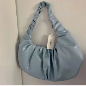 Axelväska  - blå axelväska från nelly i nyskick! inte kommit till någon användning därav prislappen kvar